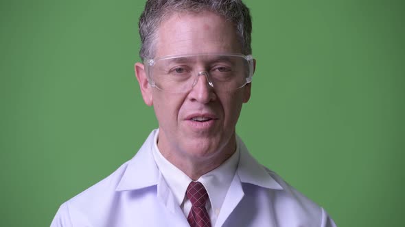 Mature Man Doctor with Protective Glasses Having an Interview