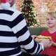 Father gives a Christmas gift to his daughter dressed in festive red dress - VideoHive Item for Sale
