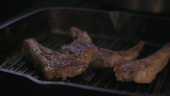 Lamb Ribs in Spices on a Grill are Being Flamed By Gas Burner