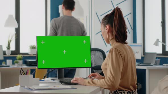 Woman Working with Isolated Green Screen on Monitor at Desk