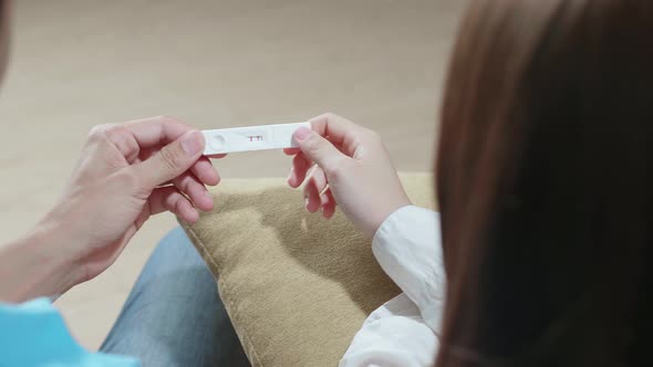 Over The Shoulder Shot Of Couple Holding Pregnancy Test, New Life And New Family Concept