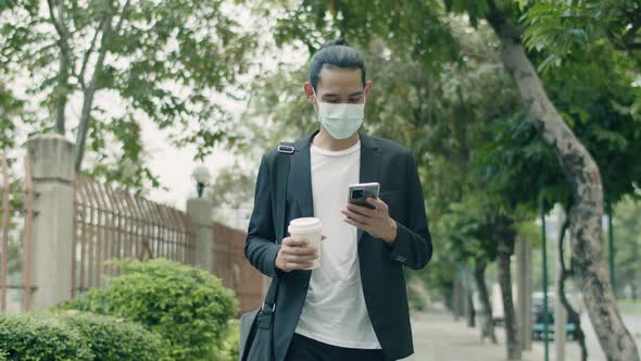 Asian businessman wearing a surgical mask and using smartphone.