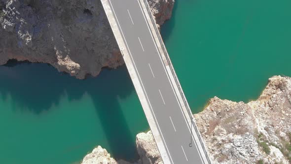 Empty car bridge over river with turquoise clear water and mountain cliffs