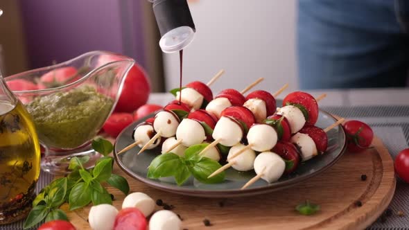Pouring Balsamic Sauce on Caprese Canapes with Cherry Tomatoes and Mozzarella Cheese Balls