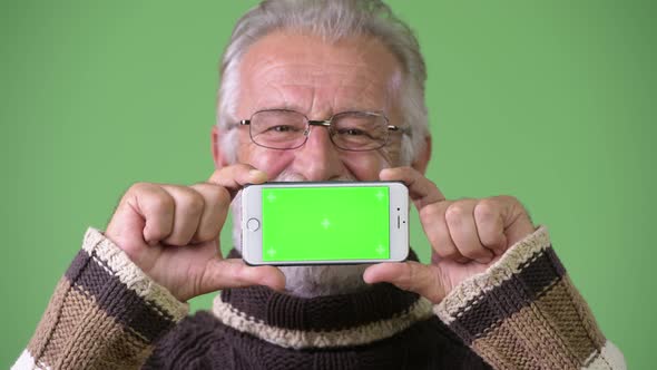 Handsome Senior Bearded Man Wearing Warm Clothing Against Green Background