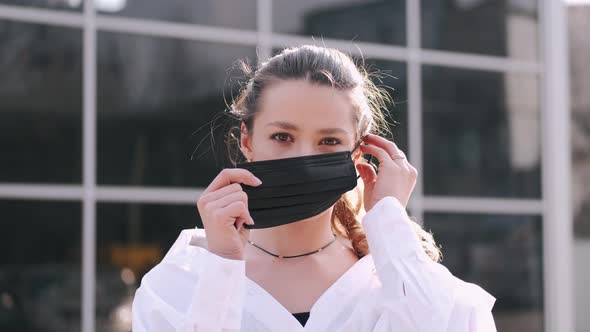 A Pretty Girl Is Putting a Protective Mask on and Showing Stop Sign By Hand