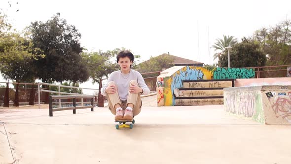 Teenage Girl Rides Sitting on a Skateboard