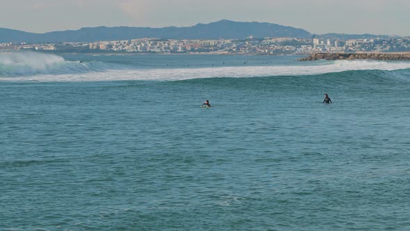 People swimming on surfing boards in the ocean near the Lisbon coast, Portugal