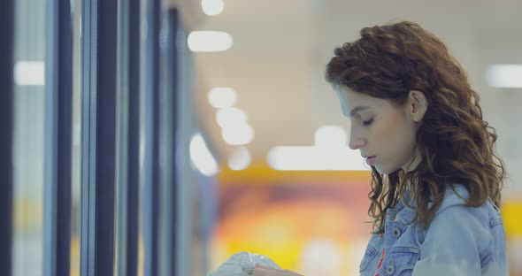 Young Girl Chooses Frozen Foods From the Refrigerated Display Case in the Supermarket