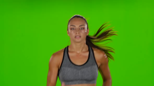 Female Runner with a Slender Figure Is Running. Front View. Green Screen