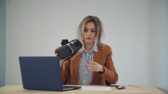 Young Beautiful Woman Taking Off Vr Glasses and Watching Laptop Screen at Office Table.