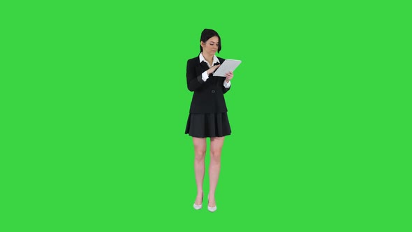 Cute Woman in Skirt Dancing and Using Digital Tablet on a Green Screen, Chroma Key.