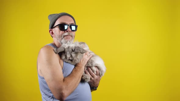 Old hipster man holding a cute bunny on hands.