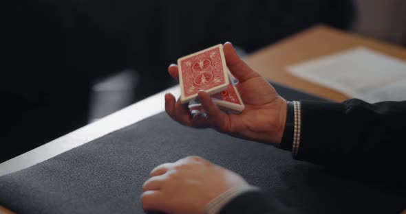 A pair of hands shows the technique how to split the deck and stack it, both one handed and with bot