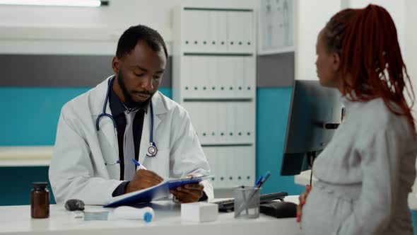 Male Physician Talking to Patient with Pregnancy Belly