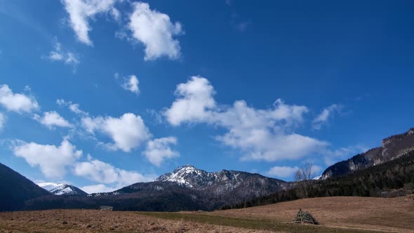 Mountain pastures in spring, the last snow on the mountain ridges, clouds in the blue sky in motion
