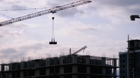 Tower Crane on a Construction Site Lifts a Load at High-rise Building.