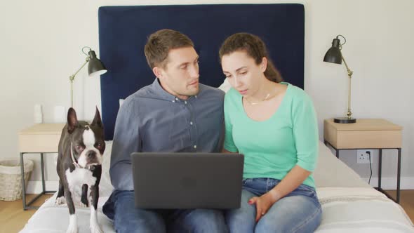 A young caucasian couple talking and paying their bills using a laptop