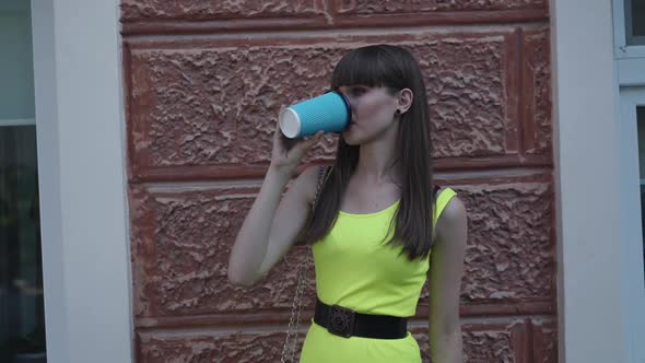 Happy Female Teen in Light Green Dress Drinks Beverage and Poses with Smile