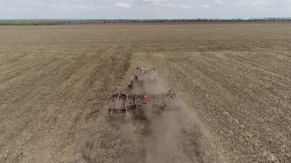 Tractor Ploughing a Field with a Trail of Dust Behind it