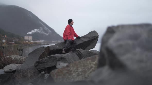 Hiker On Rocks Looking Out To Fjord