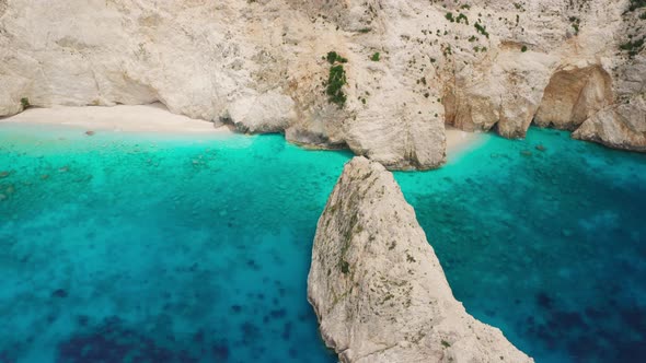 Aerial view at coastline with tall stone cliff and rock island, turquoise sea.