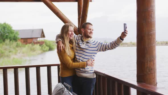 Caucasian couple spending time at home together, taking a photo outside the cabin