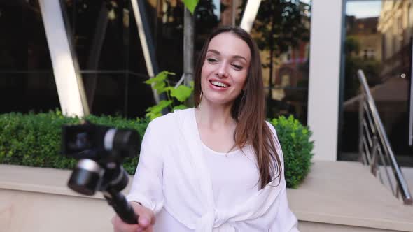 Woman filming video on camera near modern office building. 