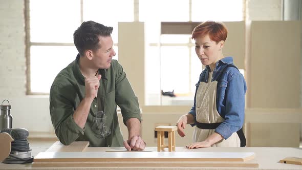 Two Young Carpenters Working As Wood Designers in Small Carpentry Workshop