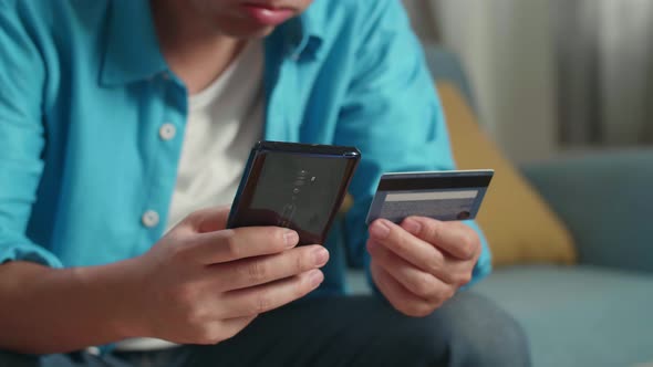 Close Up Of A Man Holding Credit Card And Smartphone Shaking His Head Due To Unable Pay Money