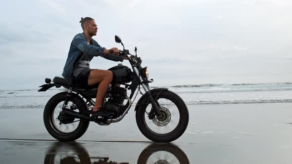 Man in Riding Motorcycle on Beach. Vintage Motorbike on Beach Sunset on Bali. Young Hipster Male