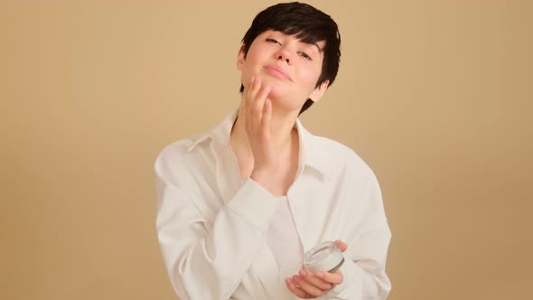 Young woman applying moisturizing cream on her face daily beauty skin