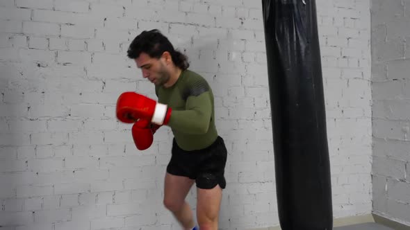 Man Boxer in Gloves Training To Kick Punch Bag