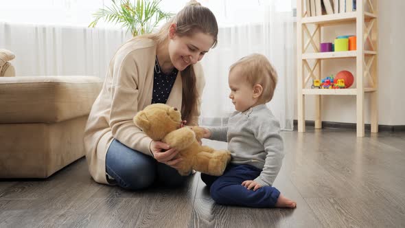 Mother playing with her baby son with teddy bear