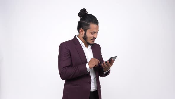Happy Indian businessman doing calculations using calculator