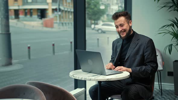 Bearded man is negotiating a zoom call in a coffee shop.Freelancer, businessman.