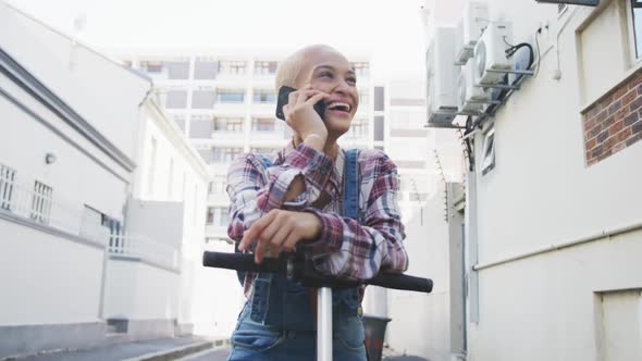 Mixed race woman on electric scooter and on a phone call