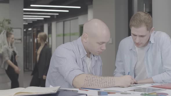 Portrait of Two Excited Male Colleagues Talking Shaking Hands in Office Hugging