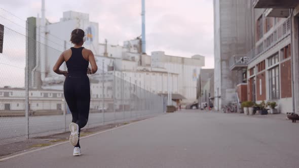 Young Woman In Black Sportswear Jogging Along Harbour