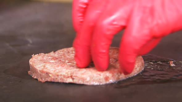 Closeup Side View Hands in Red Gloves Put Cutlet in Hot Oil