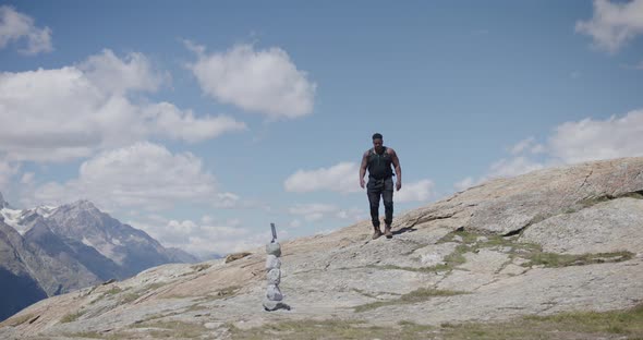 Black male traveler with backpack getting up and walking along scenic mountainside near the Matterho