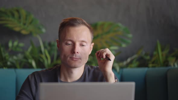 Thoughtful Serious Young Man Student Writer Sit at Home Office Desk with Laptop Thinking of