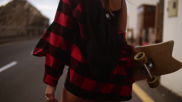 Cropped Footage Woman in Plaid Coat on a Cloudy Day at Walking Holding a Skateboard Slow Motion