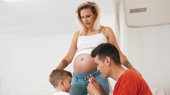Little Boy and His Dad Trying to Listen to the Heartbeat From a Pregnant Woman's Belly Happy Family