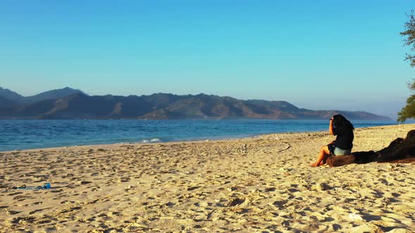 Modern happy lady on vacation by the sea at the beach on summer white sandy and blue background 4K