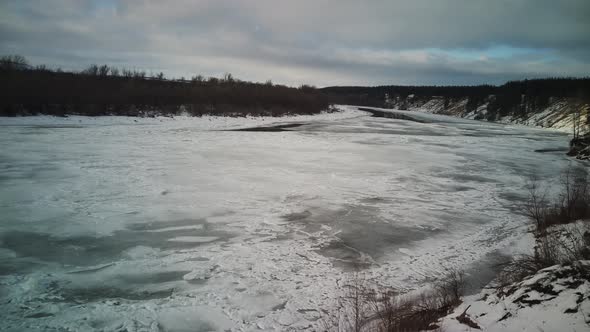Calm, frozen river covered with ice on cold winter day.