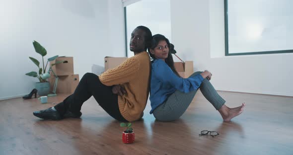 Young multi ethnic couple sitting on the floor of their new home