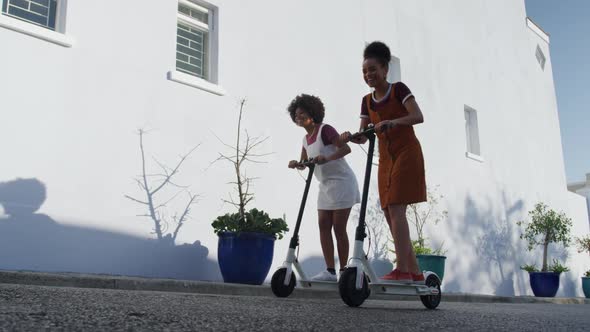 Two mixed race women riding electric scooter