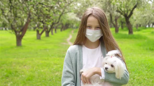 Little Girl with Dog Wearing Protective Medical Mask for Prevent Virus Outdoors in the Park