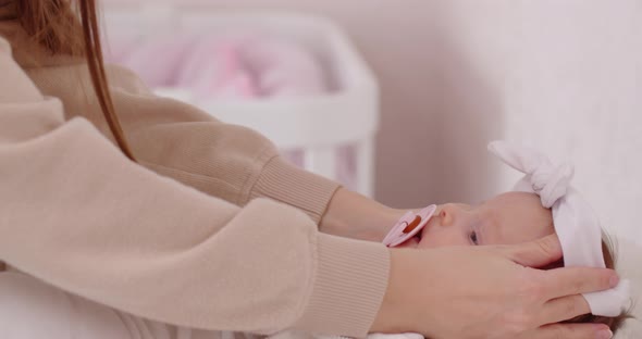 Maternal Love. A Caring Mother Dresses Her Newborn Baby